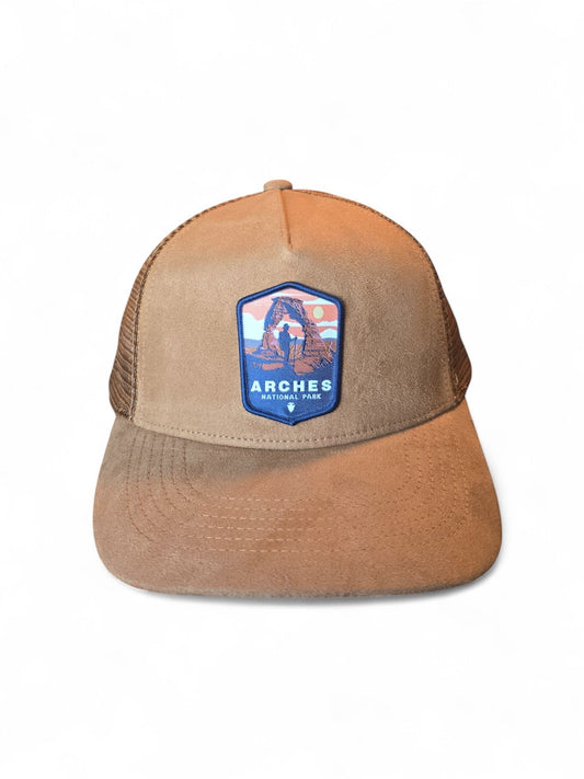 Moove Headwear tan suede trucker hat with embroidered Arches National Park patch and mesh back panels.