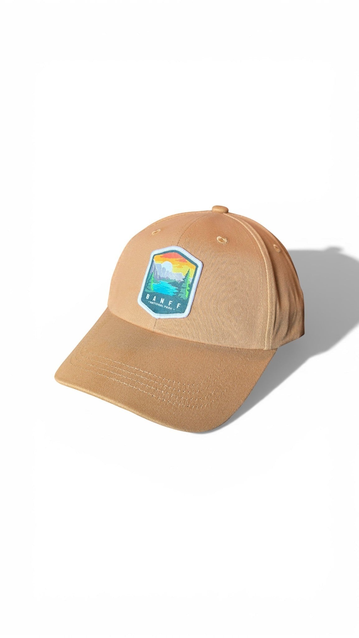 Moove Headwear tan baseball cap with embroidered Banff National Park logo patch featuring mountains, lake, and trees.