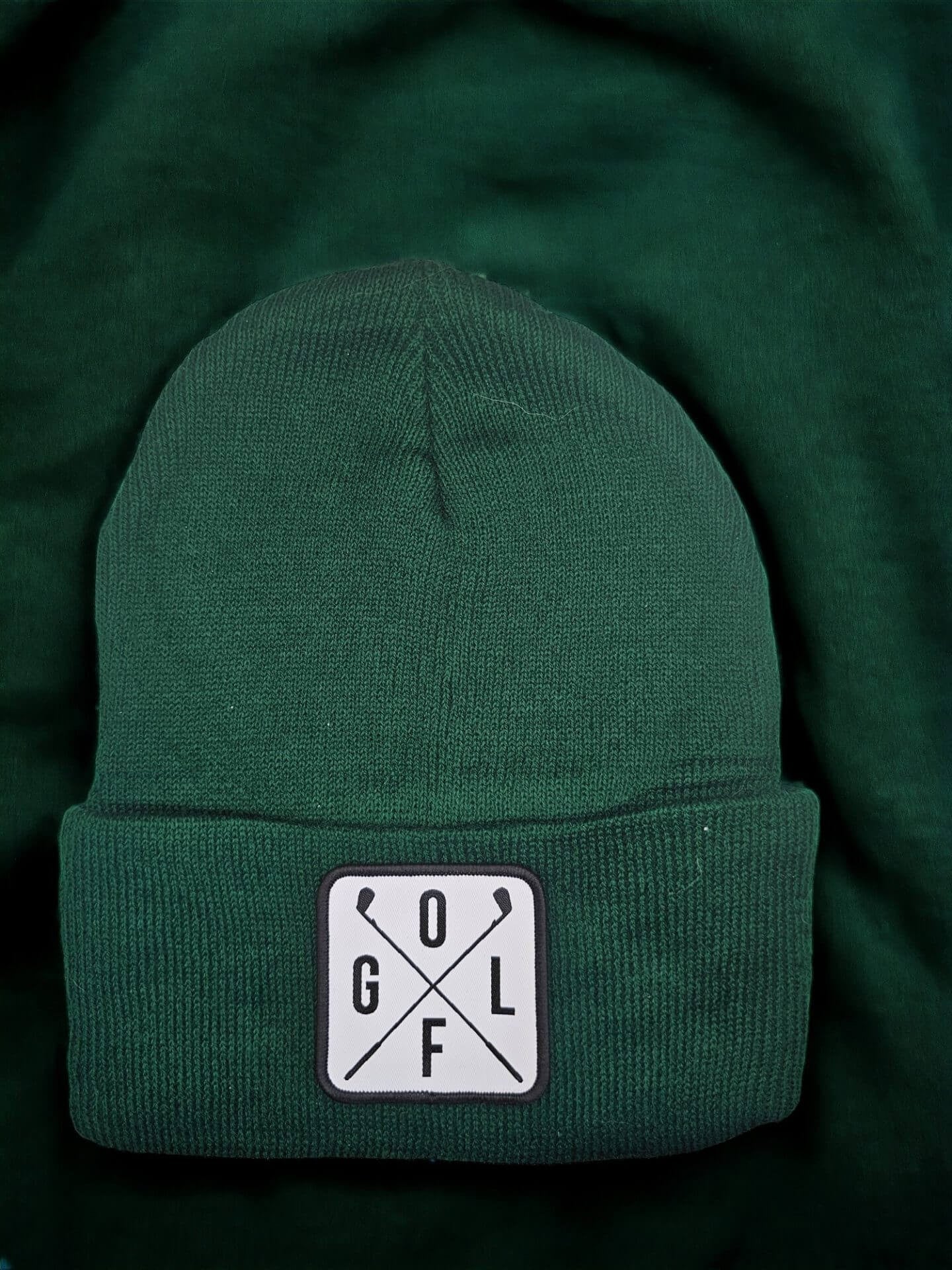 Moove Headwear dark green acrylic rib-knit golf beanie with a white square patch featuring crossed golf clubs and the letters GOLF.