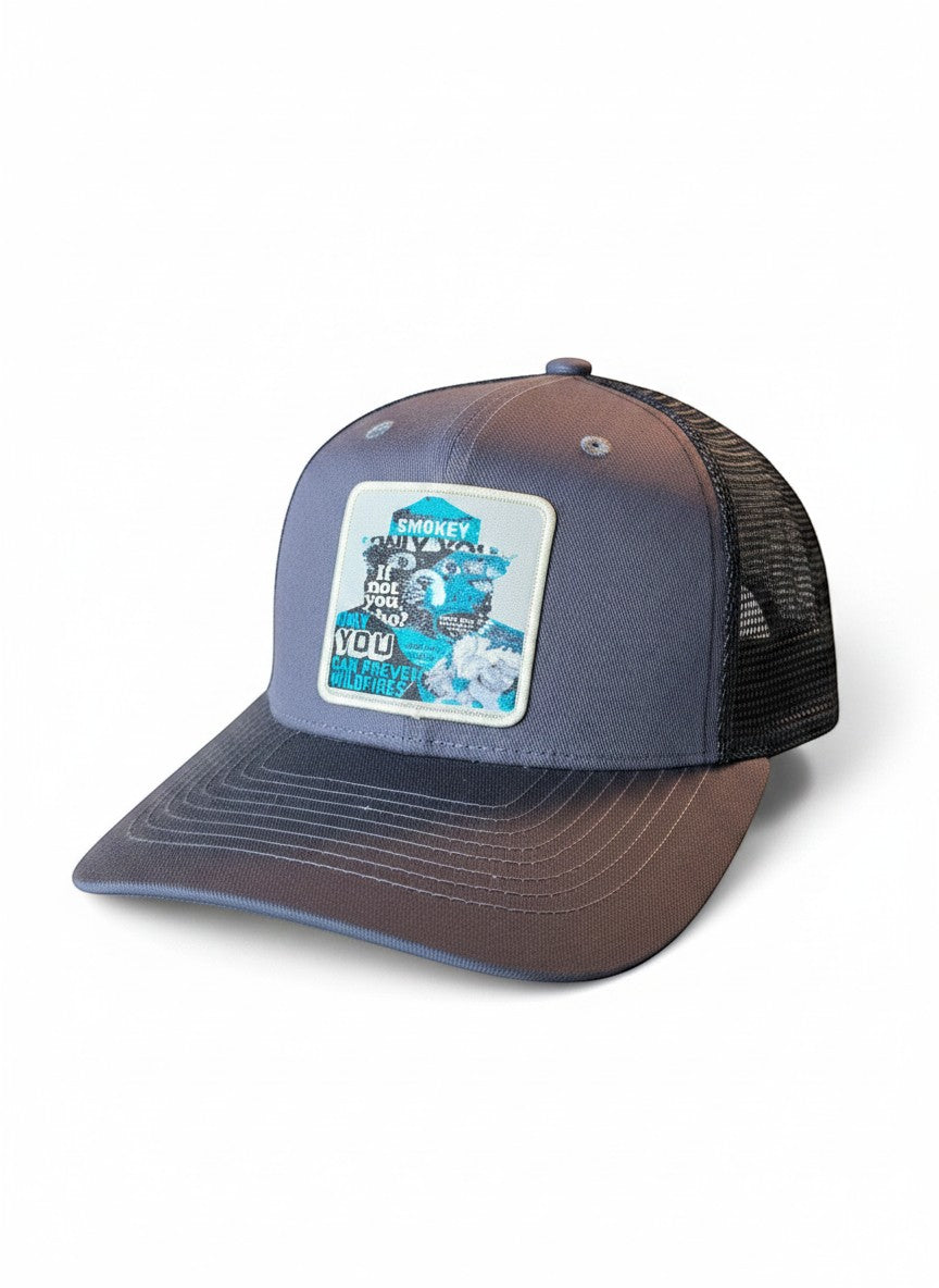 Moove Headwear grey trucker hat with Smokey Bear graphic patch and black mesh back. Adjustable snapback closure.