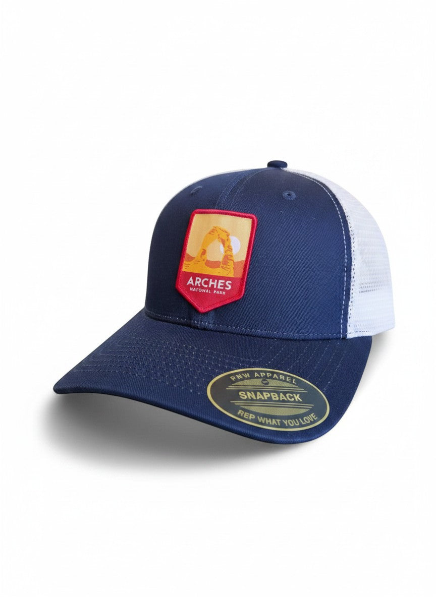 Moove Headwear navy blue trucker hat with Arches National Park embroidered patch and white mesh back.