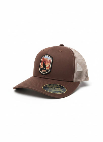Moove Headwear brown trucker hat with embroidered Arizona desert patch and mesh back. Adjustable snapback for a classic fit.