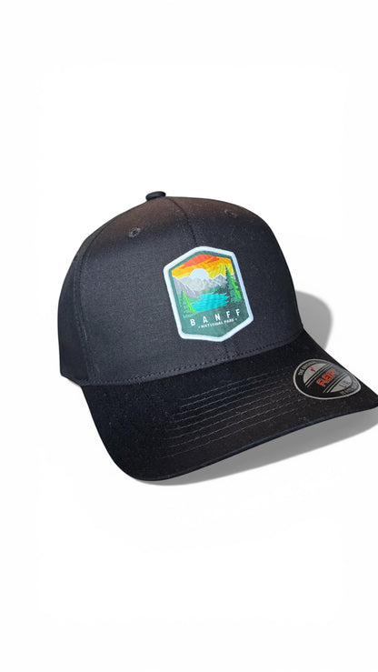 Moove Headwear black fitted cap with Banff National Park embroidered patch. Features a mountain and lake scene.