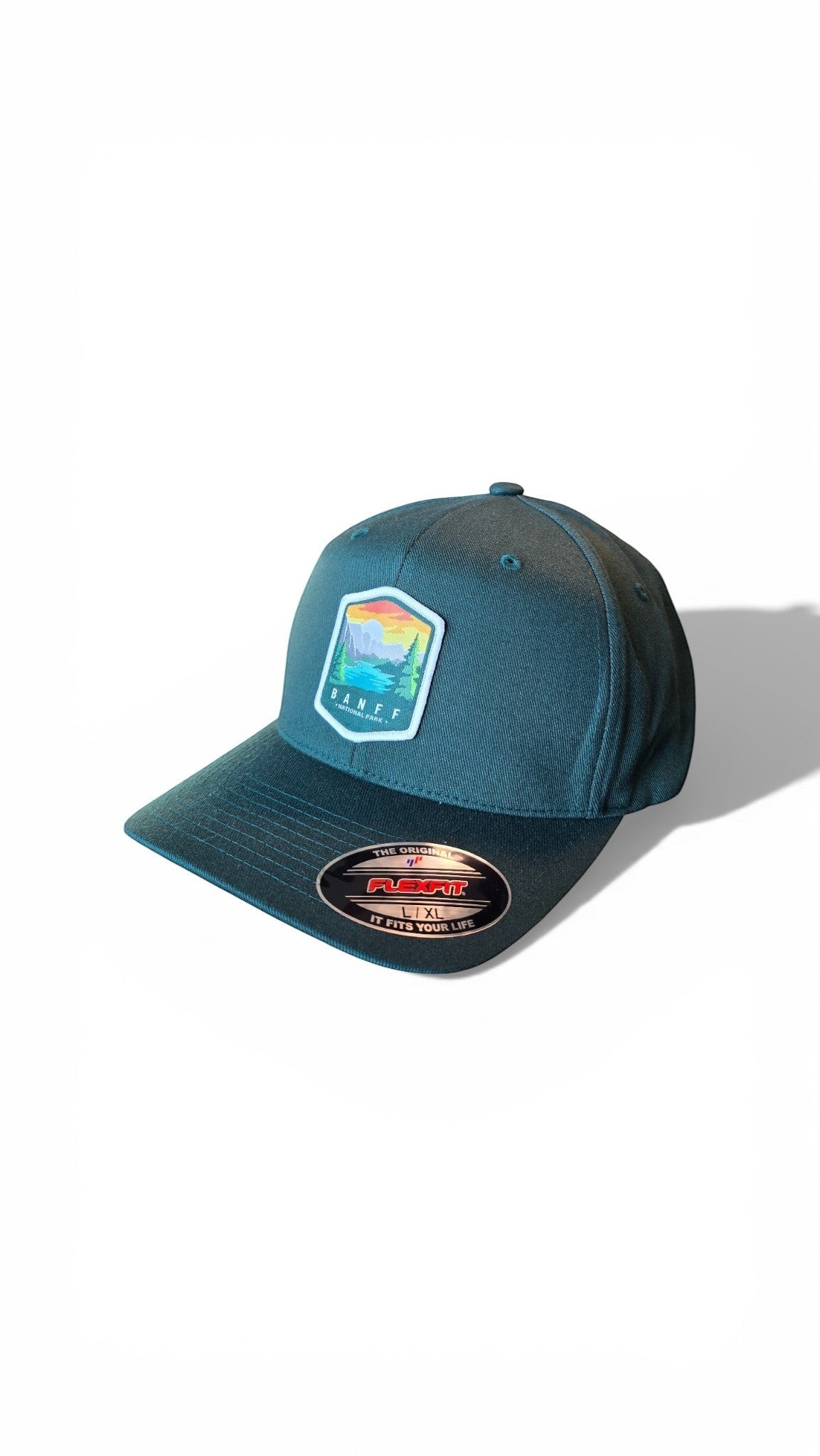 Moove Headwear Banff National Park fitted cap in teal, featuring a patch with mountains, trees, and a rainbow. Breathable fabric.
