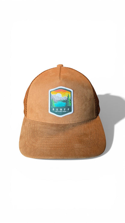 Moove Headwear Banff National Park suede trucker hat with embroidered mountain and lake scene patch.