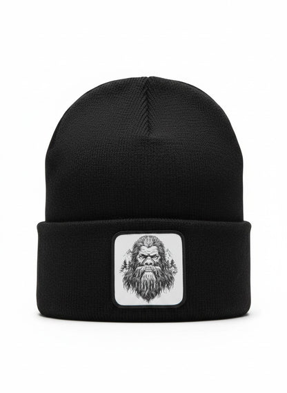 Moove Headwear black acrylic knit beanie with a woven patch featuring a Bigfoot illustration and pine trees.