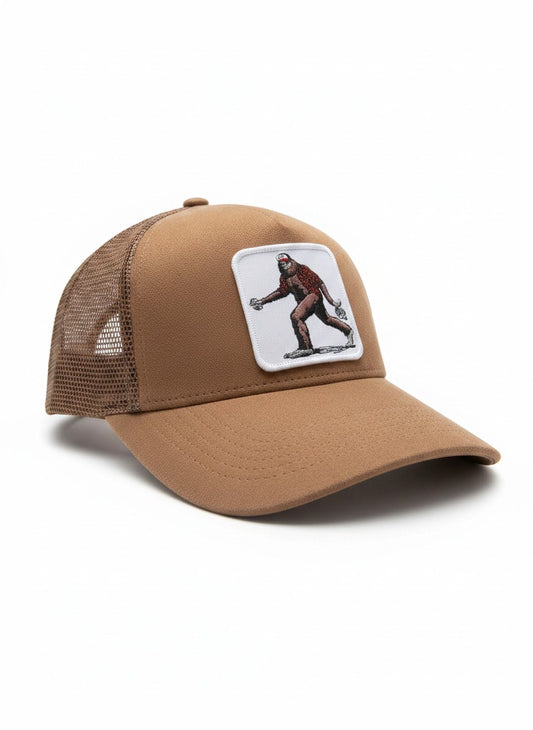 Moove Headwear tan suede trucker hat with Bigfoot patch and mesh back panels. Adjustable snapback closure.
