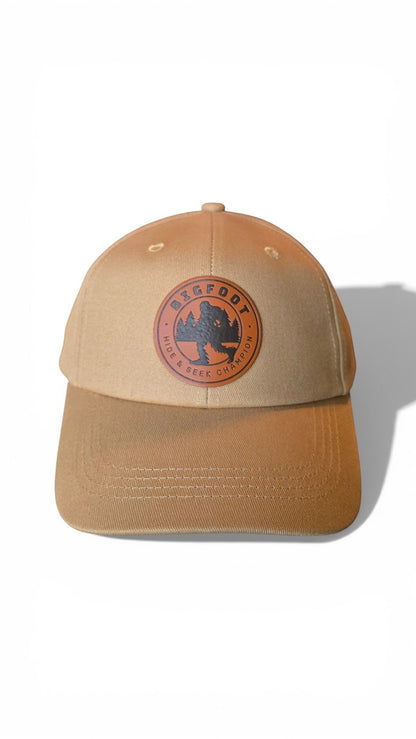 Moove Headwear tan trucker hat with Bigfoot Sasquatch leather patch and adjustable strap.