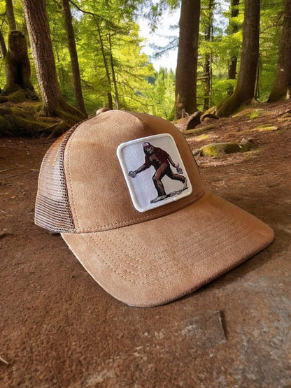 Moove Headwear tan suede trucker hat with Bigfoot patch and mesh back. Adjustable snapback for a secure fit.