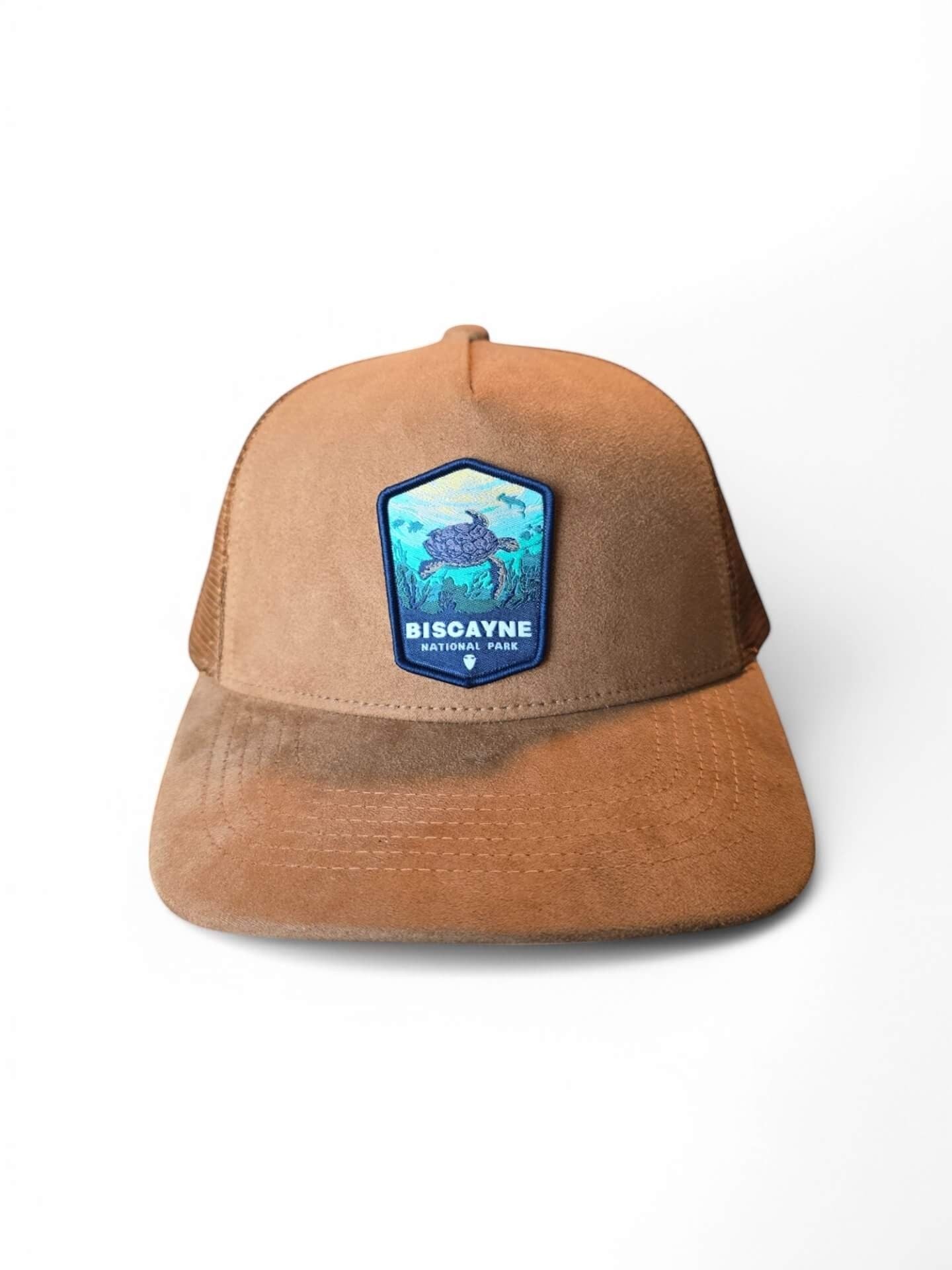 Moove Headwear tan suede trucker hat with mesh back and Biscayne National Park turtle patch. Adjustable snapback.