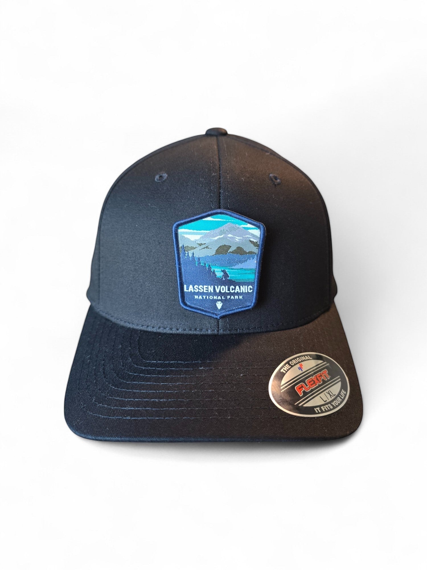 Moove Headwear black Flexfit cap with embroidered Lassen Volcanic National Park patch featuring mountains and forest.