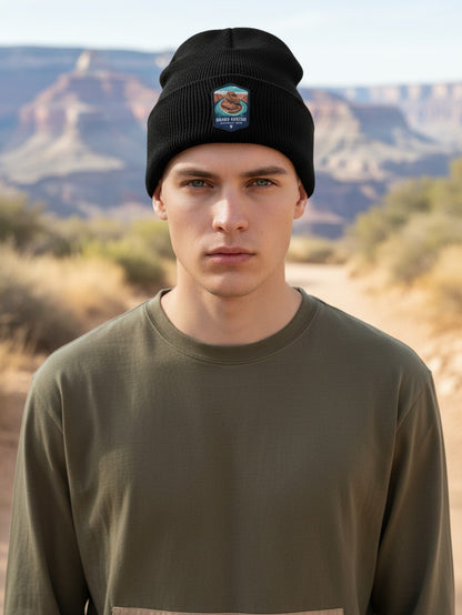 Man wearing a black Moove Headwear rib-knit beanie with a Grand Canyon embroidered patch in a desert landscape