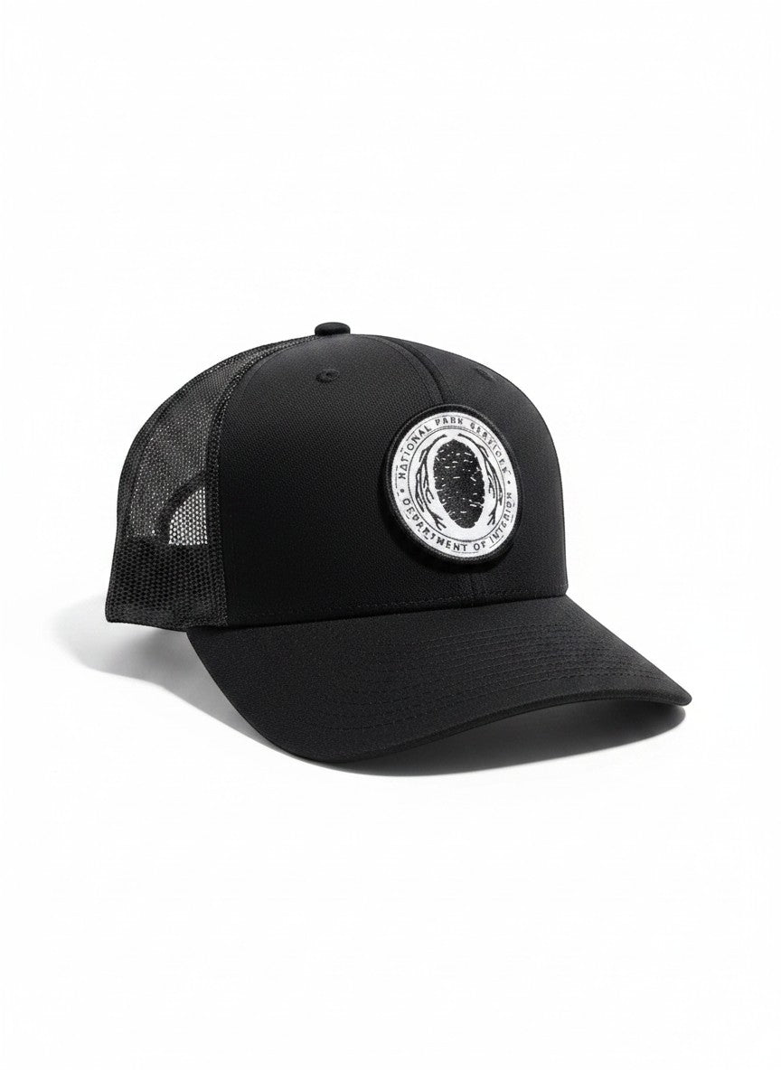 Moove Headwear black trucker hat with National Park Service Sequoia Cone embroidered patch, mesh back, and snapback closure.