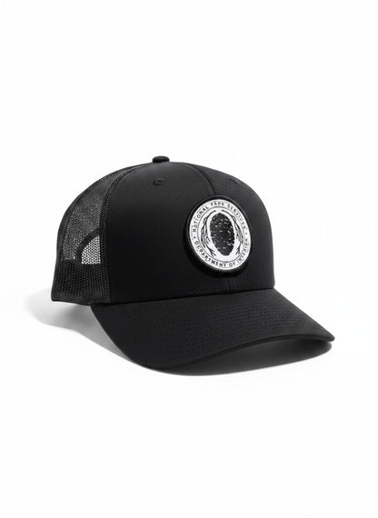 Moove Headwear black trucker hat with vintage National Park Service Sequoia Cone embroidered patch. Features mesh back and snapback closure.