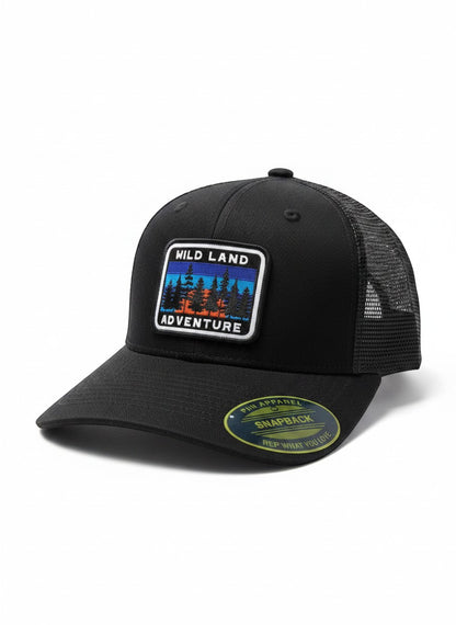 Moove Headwear black trucker hat with mesh back and a "Wild Land Adventure" patch featuring trees and a sunset.