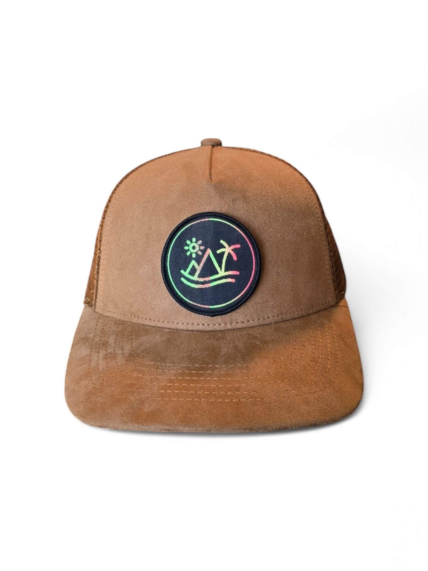 Moove Headwear brown suede trucker hat with breathable mesh back and circular patch featuring a sunset over mountains and palm trees.