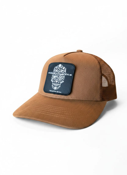 Moove Headwear brown suede trucker hat with mesh back and National Park Service skull patch. Adjustable snapback.