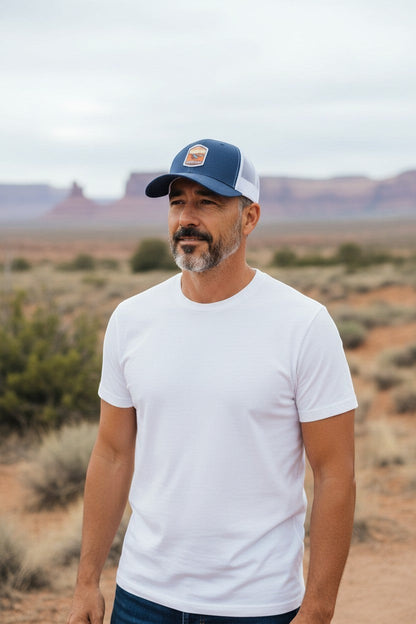 Moove Headwear navy blue trucker hat with white mesh back and Canyonlands National Park emblem, worn by a man outdoors.