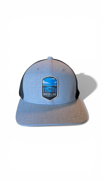 Moove Headwear light blue snapback hat with black mesh back and Crater Lake National Park embroidered patch.
