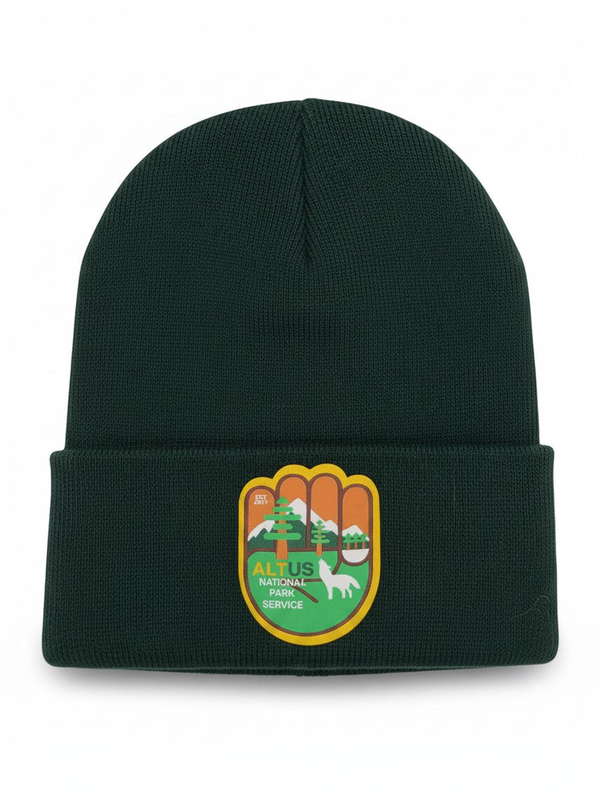 Moove Headwear dark green cuffed knit beanie with an AltUs National Park patch featuring a wolf and mountain design.