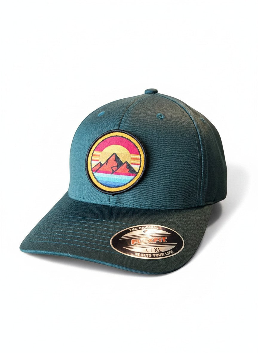 Moove Headwear dark teal Flexfit hat with retro sunset mountain patch. Features embroidered mountains, sun, and rainbow stripes.