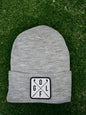 Moove Headwear grey acrylic knit beanie with a white square patch featuring crossed golf clubs and the word GOLF.