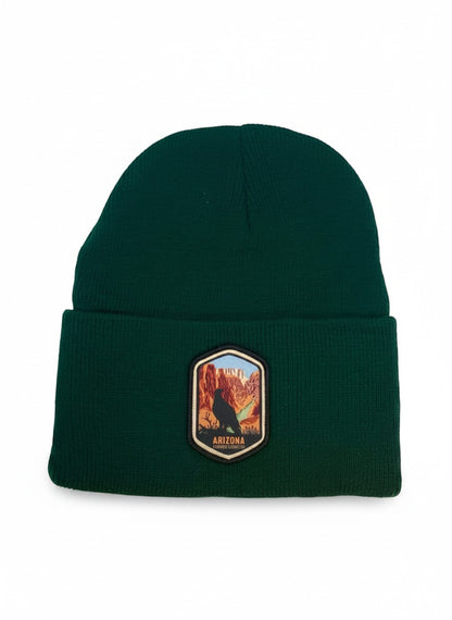 Moove Headwear dark green acrylic rib-knit beanie with a woven patch featuring a bird and the Grand Canyon.