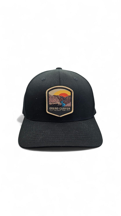 Moove Headwear black Flexfit cap with embroidered Grand Canyon National Park logo patch, featuring a sunset over the canyon and river.