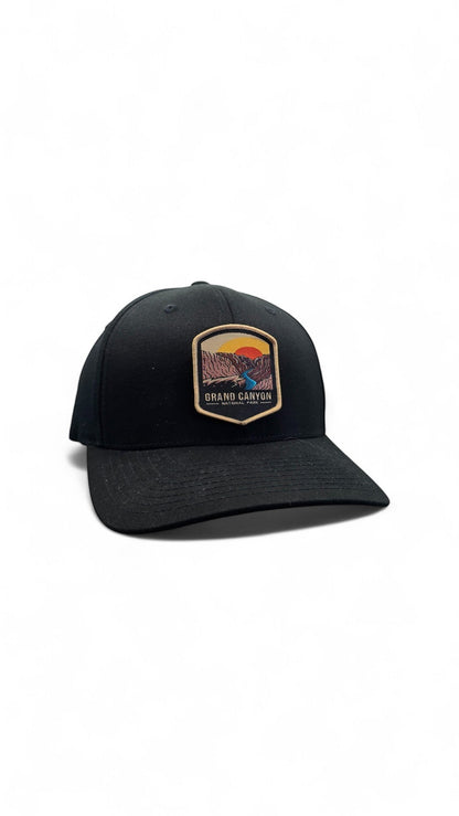 Moove Headwear black Flexfit baseball cap with embroidered Grand Canyon National Park logo patch. Features a sunset over canyon and river.