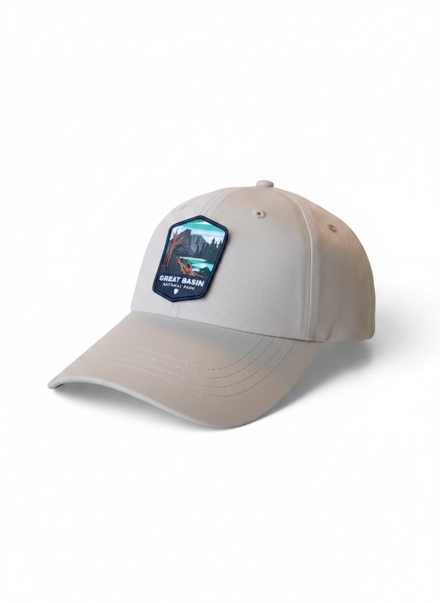 Moove Headwear Great Basin National Park trucker hat in light beige with a woven patch featuring mountains and trees. Adjustable fit.