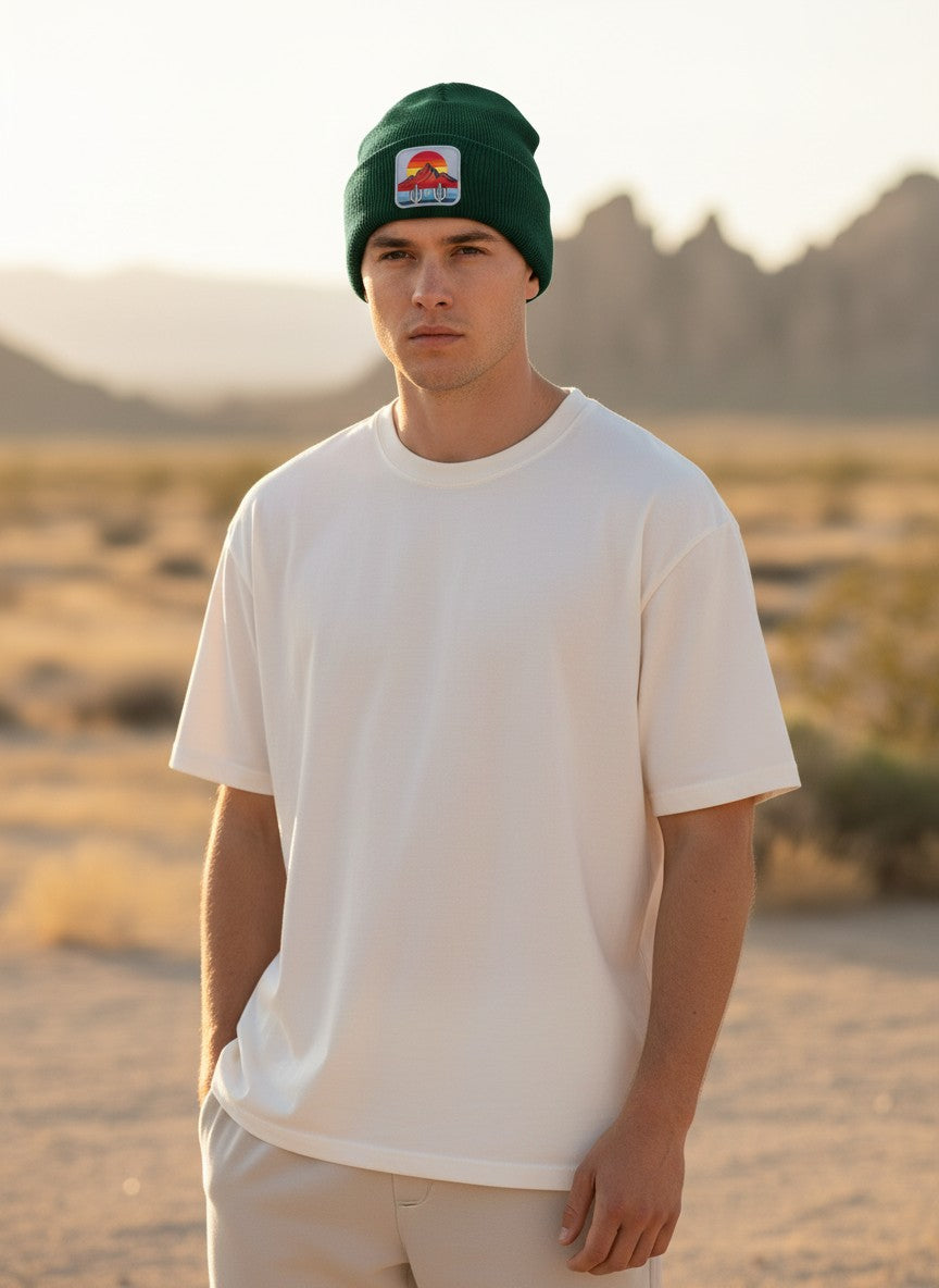 Man wearing a Moove Headwear dark green knit beanie with a desert sunset cactus patch in a desert landscape