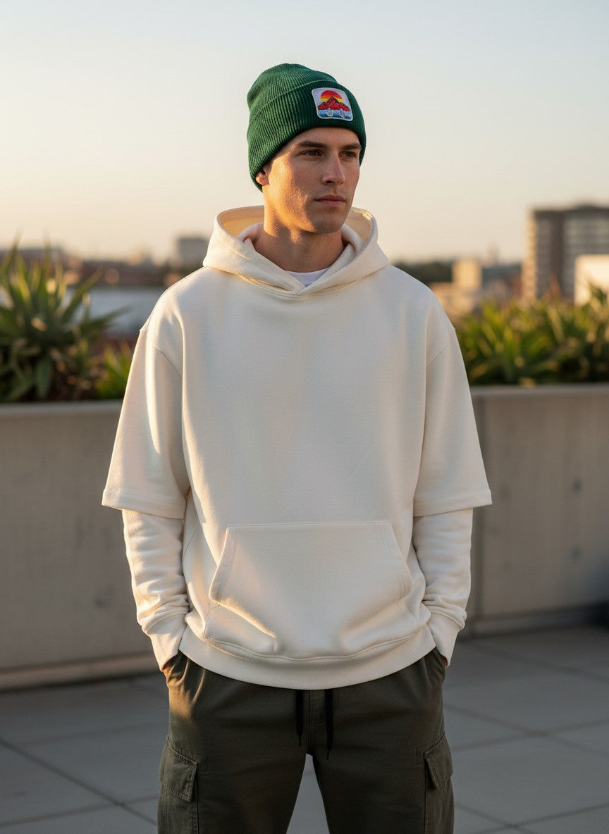 A man wearing a Moove Headwear green knit beanie with a desert sunset cactus patch outdoors at sunset.