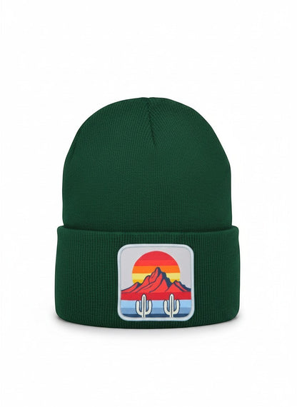 Moove Headwear dark green knit beanie with a square patch featuring a desert sunset, mountains, and cactus design.