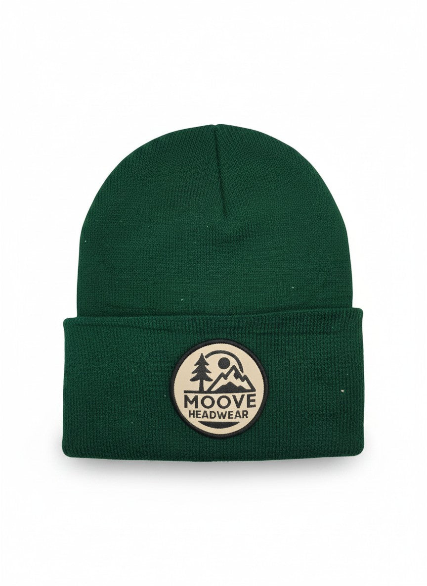 Moove Headwear forest green knit beanie with fold-over cuff and circular logo patch featuring mountains and trees.