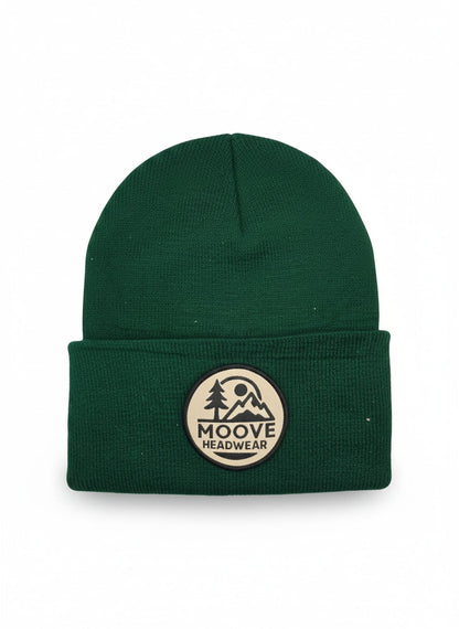 Moove Headwear forest green knit beanie with fold-over cuff and circular logo patch featuring mountains and trees.