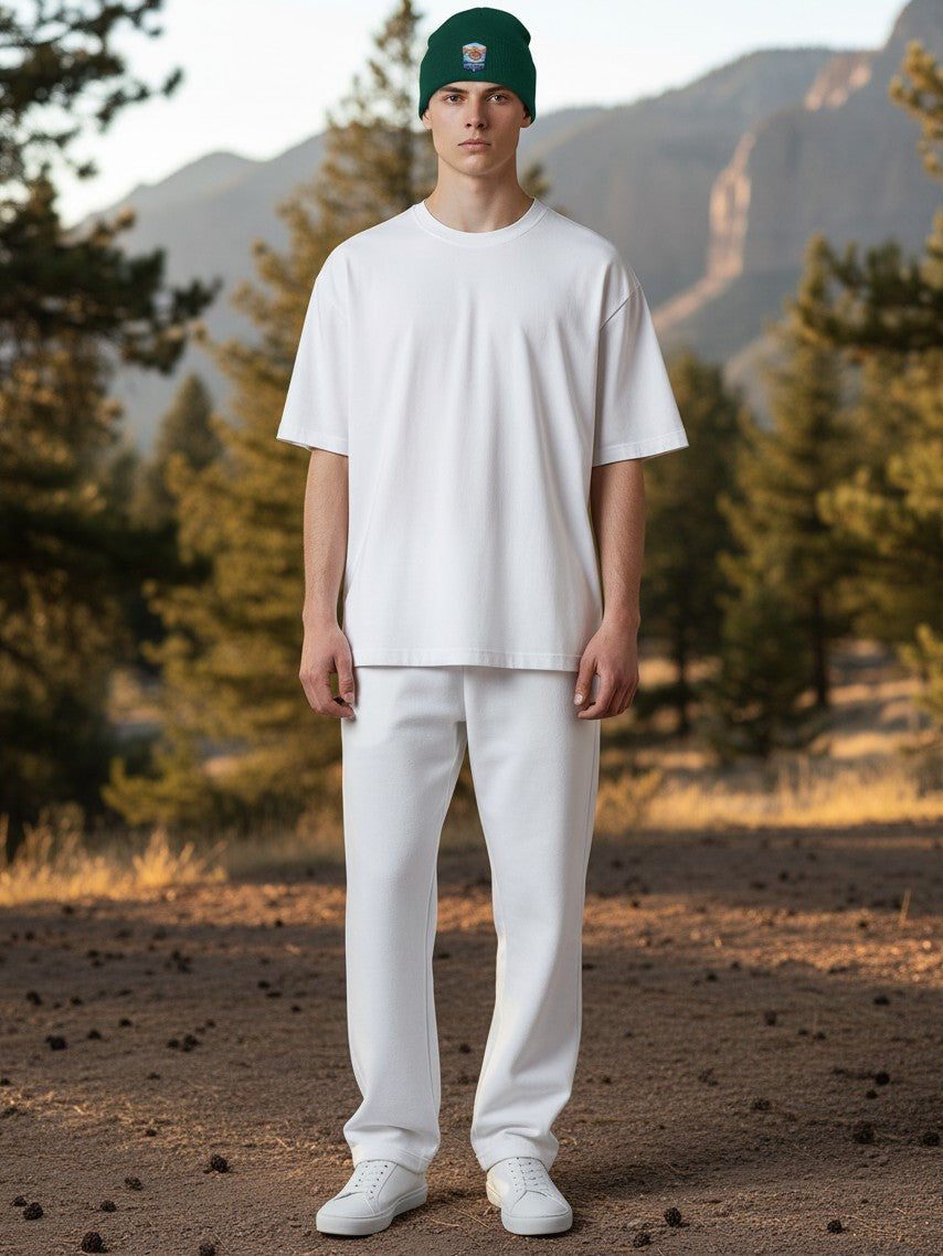 Moove Headwear green rib-knit beanie with Grand Canyon patch worn by a man in a white outfit in a forest setting