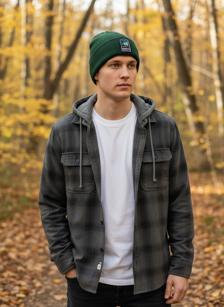 A man wearing a green Moove Headwear Mammoth Cave National Park rib-knit beanie in a scenic autumn forest.