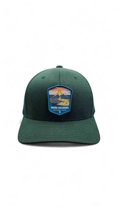 Moove Headwear deep green fitted cap with embroidered Hawaii Volcanoes National Park patch featuring a lava and sunset scene.