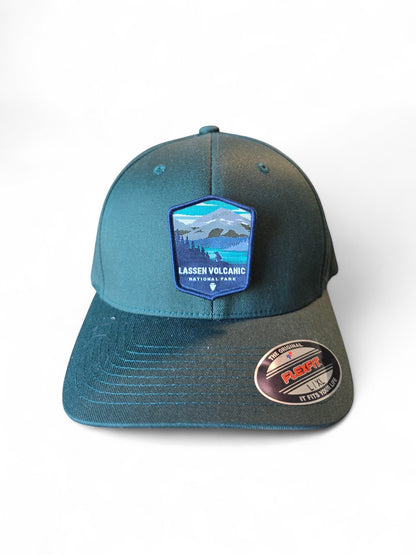 Moove Headwear black Flexfit cap with embroidered Lassen Volcanic National Park patch featuring mountains and forest.