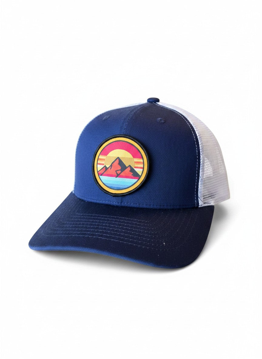 Moove Headwear navy blue trucker hat with a retro mountain sunset patch and white mesh back.