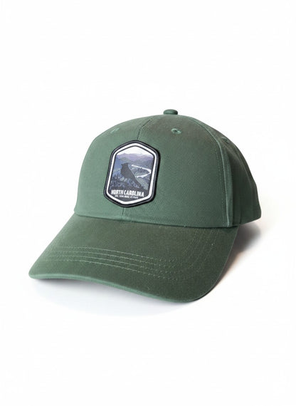 Moove Headwear green cotton adjustable baseball cap with a woven patch featuring a scenic North Carolina landscape and text.