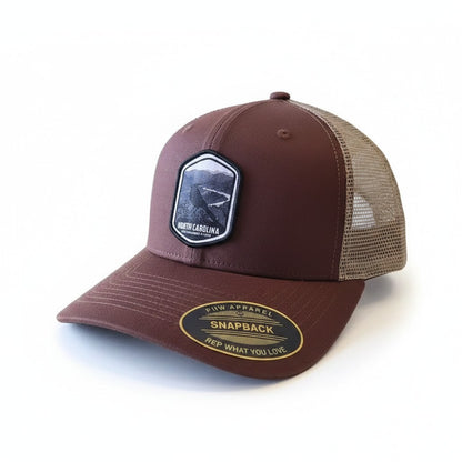 Moove Headwear North Carolina Tar Heels trucker hat with mesh back and embroidered patch. Brown fabric.