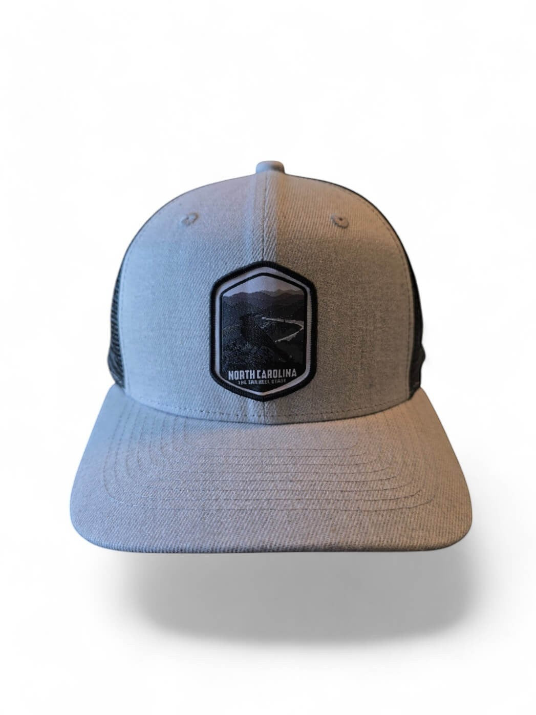 Moove Headwear light grey trucker hat with black mesh back and embroidered North Carolina patch.