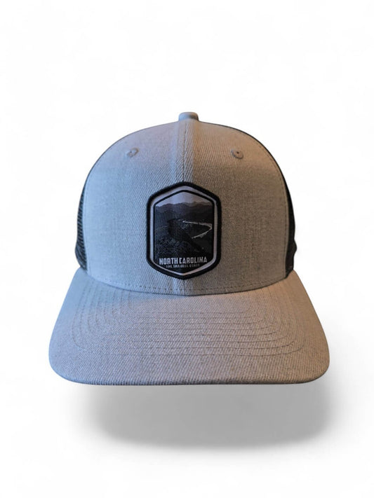 Moove Headwear light grey trucker hat with black mesh back and embroidered North Carolina patch.
