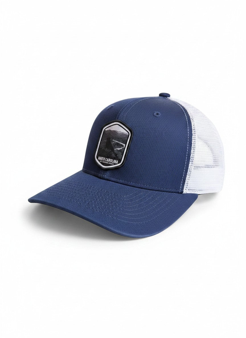 Moove Headwear navy blue trucker hat with white mesh back and embroidered North Carolina patch.
