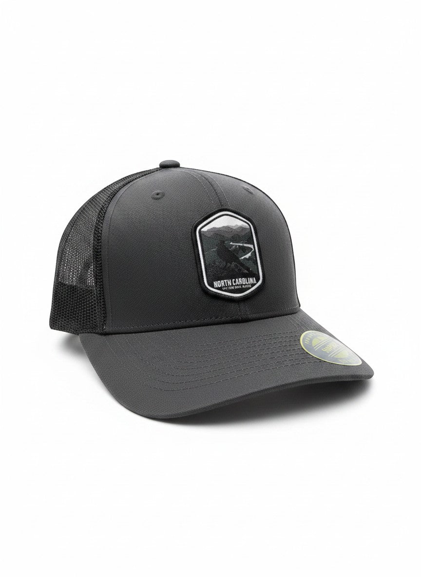 Moove Headwear dark grey trucker hat with embroidered North Carolina patch and mesh back. Adjustable snapback closure.