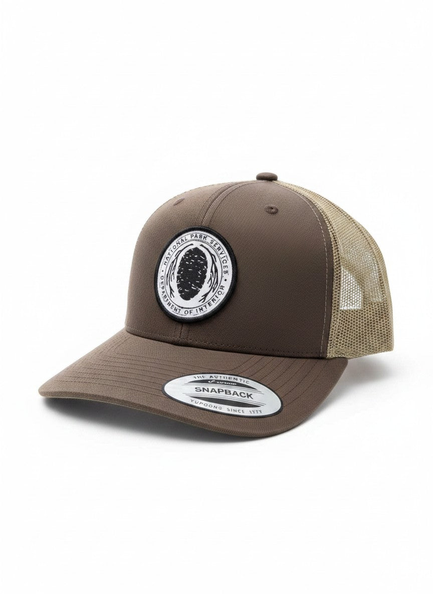 Moove Headwear vintage brown trucker hat with embroidered National Park Service Sequoia Cone patch and mesh back.