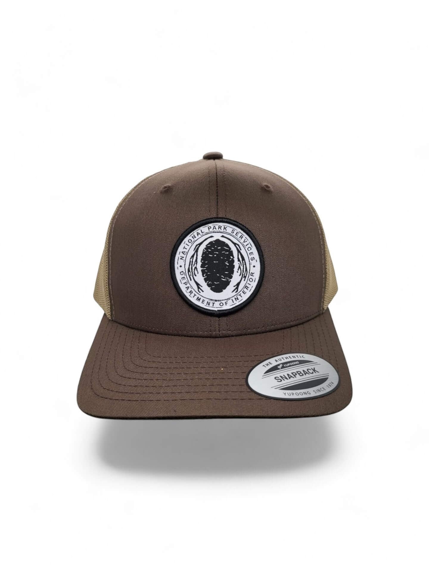 Moove Headwear brown trucker hat with National Park Service Sequoia Cone embroidered patch and tan mesh back.