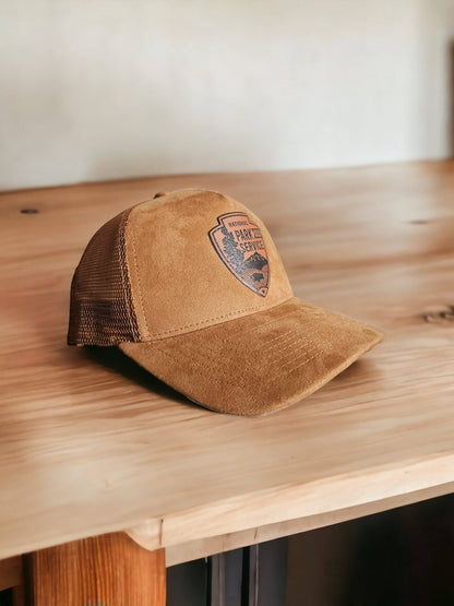 Moove Headwear tan suede trucker hat with National Park Service leather patch and mesh back panels.