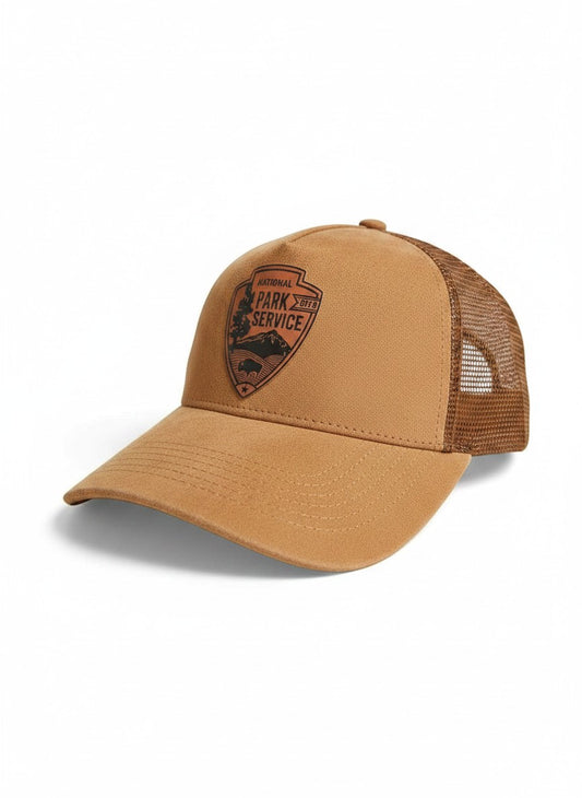 Moove Headwear tan suede trucker hat with National Park Service leather patch emblem and mesh back.
